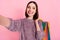 Photo of pretty shopaholic lady shoot selfie carry mall bags wear knitted sweater  pink color background