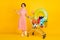 Photo of promoter girl hold cart sports goods hand hold empty space wear striped dress isolated yellow color background