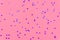 Photo of purple hearts glitter sprinkles on pink trendy background. Festive holiday background for your projects. Celebration