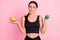 Photo of questioned unsure young woman dressed sportive outfit holding potato crisps dumbbell isolated pink color