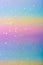 Photo of a rainbow-colored paper surface with glitter. Abstract blurred multi-colored pastel background with sequins