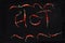 Photo of Red chillies arranged to spell hot on a black Background,
