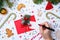 Photo of red envelope, cookies, hands with pen, branches of spruce Christmas decorations