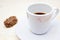 A photo of the red lipstick marks on your coffee cup. Dirty empty white porcelain cup on the plate and a chocolate candy. Messthet