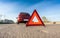 Photo of red triangle sign on road next to broken car