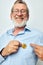 Photo of retired old man in blue shirts bitcoin in hands light background