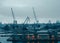 Photo of river, floating cranes, buildings on river bank