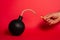 Photo of a round bomb with lit fuse on a red background. Big bomb on red background. Vertical