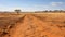 A photo of the rugged Australian Outback, with vast open plains as the background, during a scorching hot afternoon