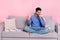 Photo of sad sick arabian man wear long sleeve shirt sitting sofa coughing isolated pink color background