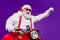 Photo of santa claus role man rapid riding newyear party by bike excited to see friends using super powers to move fast