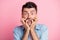 Photo of scared shocked young man bite nails hold hands mouth isolated on pastel pink color background