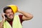 Photo of screaming builder in yellow helmet with walkie-talkie on empty gray background.