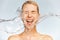 Photo of  screaming woman with drops of water around her face. Young woman with clean skin and splash of water.  Spa treatment.
