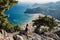 Photo of a sea landscape, view of Tsambika Bay on the island of Rhodes. Girl sits on a stone and looks at a beautiful sandy beach