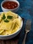 In the photo we see a portion of ravioli drizzled with melted butter. On top is a sprig of fresh parsley. There is a fork to the