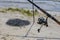 photo with selective focus  fishing rod with profesional reel standing on the sand near the pond sunny summer day