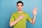 Photo of serious confident young guy dressed green t-shirt rising palm swearing tell truth isolated blue color