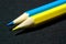 Photo of sharpened yellow and blue pencils close-up lying in a row on a dark background