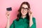 Photo of shiny cute lady wear green shirt arm eyeglasses rising bank card isolated pink color background