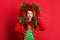 Photo of shiny impressed young woman dressed ugly pullover smiling holding christmas wreath isolated red color