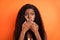 Photo of shocked amazed surprised african woman cover close mouth with hands guilty isolated on orange color background