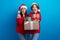 Photo of shocked cheerful women santa elves wear ornament pullovers bying x-mas gifts isolated blue color background