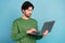 Photo of smiling focused concentrated young businessman working in computer isolated on blue color background