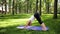 Photo of smiling happy woman 40 years old doing yoga exercises on fitness mat at forest. Harmony of human in nature