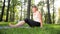 Photo of smiling happy woman 40 years old doing yoga exercises on fitness mat at forest. Harmony of human in nature