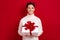 Photo of smiling positive guy wear white comfortable sweater hold desirable xmas giftbox with bright bun isolated on red