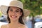 Photo of smiling young brunette woman in hat walking by street