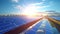 Photo of a solar farm with the sun shining through the clouds