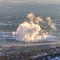 Photo Square Industrial plant emitting steam against a snow covered landscape in winter