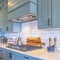 Photo Square Kitchen with white counter top and bluish gray cabinets against tile backsplash