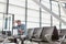 Photo of stressed mature man sitting while looking at his phone in airport