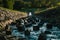 Photo of strong water stream with stones and big rocks inside flowing from reservoir dam in the high mountain area on sunset.