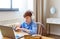 Photo of a student during an online lesson. He sits in front of a laptop monitor with headphones and attentively listens