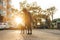 Photo of stylish woman walking dog in the evening on city background at sunset. Lady walking a puppy on a leash. Evening walk with