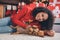 Photo of sweet adorable dark skin lady wear red pullover smiling petting puppy lying floor carpet indoors room home