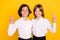 Photo of sweet adorable schoolkids formalwear showing v-signs embracing smiling isolated yellow color background