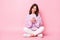 Photo of sweet charming young lady wear knitted pullover sitting floor typing device empty space isolated pink color