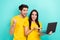Photo of sweet excited married couple wear yellow t-shirts reading news device isolated turquoise color background