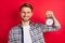 Photo of sweet handsome young gentleman dressed plaid shirt spectacles holding vintage timer isolated red color