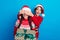 Photo of sweet impressed women santa elves wear ornament pullovers giving x-mas gifts arms cover eyes isolated blue
