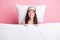 Photo of sweet pretty young woman sleepwear mask lying pillow covering duvet isolated pink color background