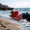 Photo Symbolic gesture Womans hand holds red heart by seashore