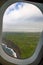 Photo taken out the window of plane, view over island with ocean and clouds