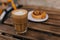 Photo of tasty cake with glass of cappuccino in focus. Cup of coffee standing on wooden table near plate with cookie..