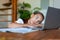 Photo of a teenage girl in front of a laptop. She's listening to a boring online lesson or doing her homework.